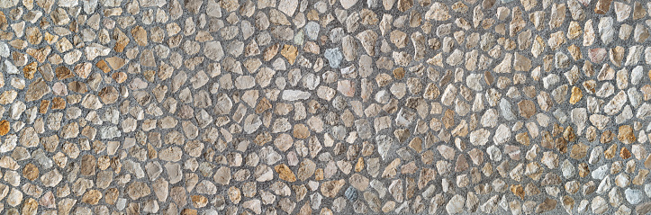 Element of an industrially manufactured stone wall made of many medium-sized natural stones in gray concrete