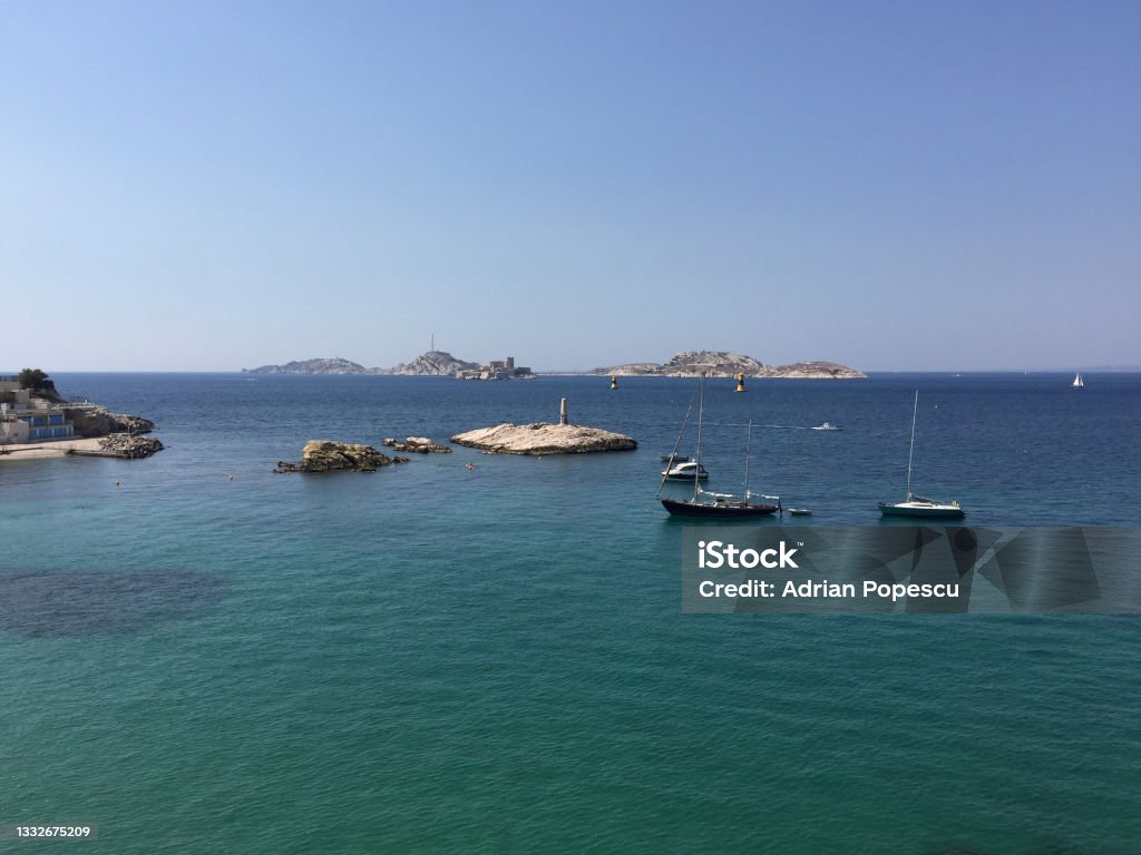 The Frioul Archipelago, with the Château d'If fortress in the center, seen from the vicinity of Malmousque port and beach in the Endoume neighborhood in Marseille, France. Marseille, France Beach Stock Photo