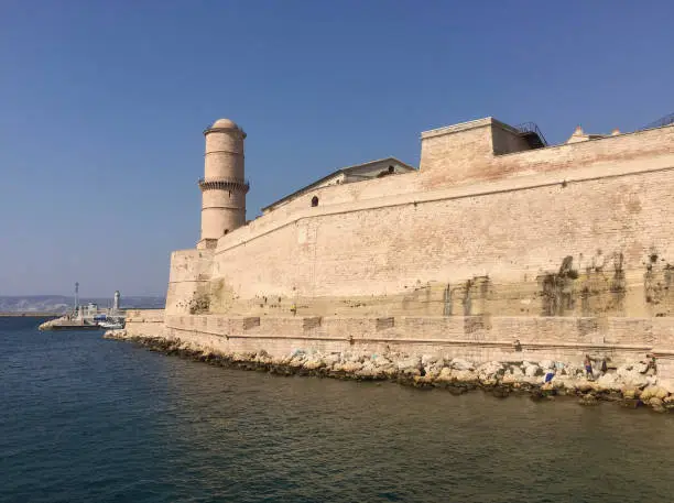 Photo of The Fort Saint Jean with the large round Tour du Fanal tower, one of the most visited monuments in Marseille. It is connected to the former port by a footbridge.