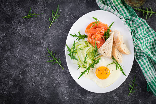 istock Diet breakfast. Salt salmon salad with greens, cucumbers, fried egg and bread.  Top view, overhead 1332676477