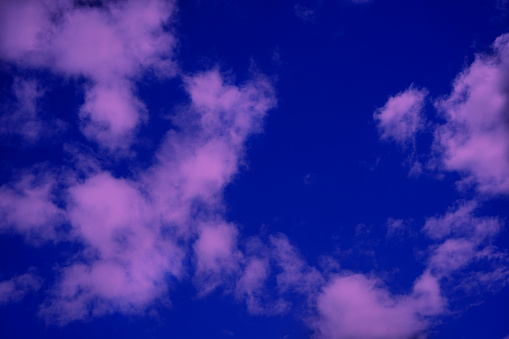 Fluffy pink clouds against the blue sky. Toned sky background for design. Web banner.