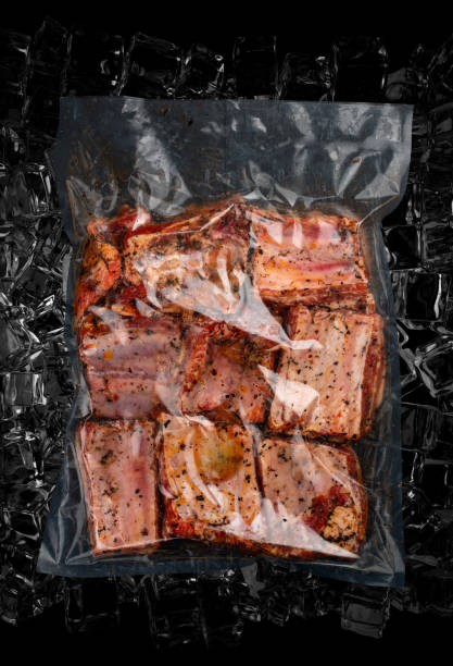 istock Vacuum-packed meat, on dark ice background, pork ribs. Semifinished.Top view. 1332679230