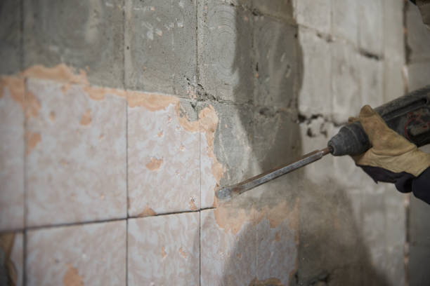 istock A young man dismantles an old tile from a concrete wall. 1332682851