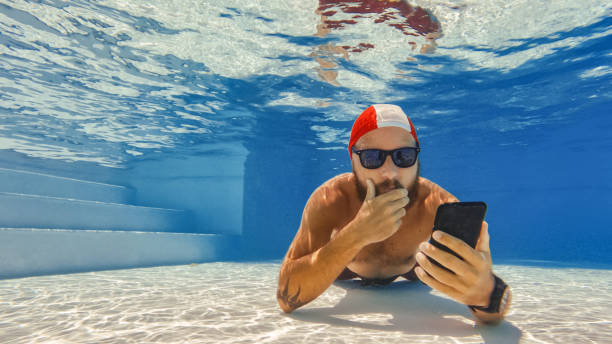 selfie drôle d’homme avec téléphone portable sous l’eau: télétravail extrême - men naked water male photos et images de collection
