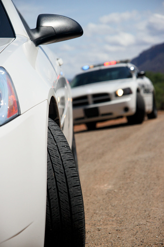 Police car that has stopped a violator in a fast police car and warned  or for other crime. Cars are blurry and unidentifiable clearly used for a prop only to depict being pulled over.