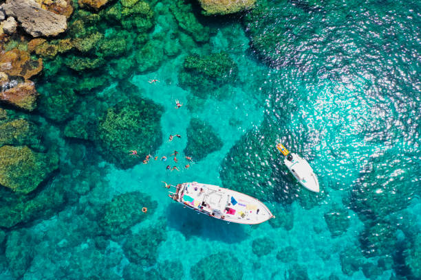 vista aérea del mar de lampedusa con dos barcos y nadadores - rock overhang fotografías e imágenes de stock
