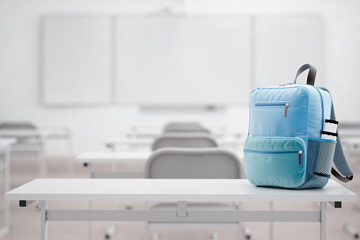 School bag on the desk in an empty modern classroom.