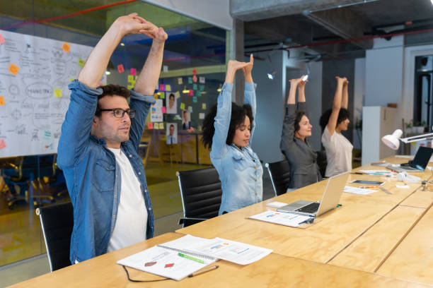 workers doing stretching exercises in a business meeting at the office - gezonde levensstijl stockfoto's en -beelden