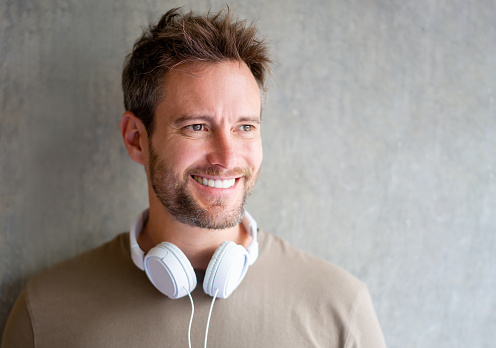 Portrait of a happy Latin American man smiling and wearing headphones around his neck