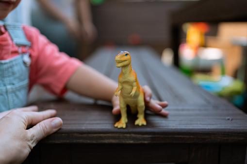 Latin toddler playing with a dinosaur toy
