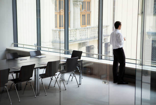istock Business man looking through window at conference room 1332700174