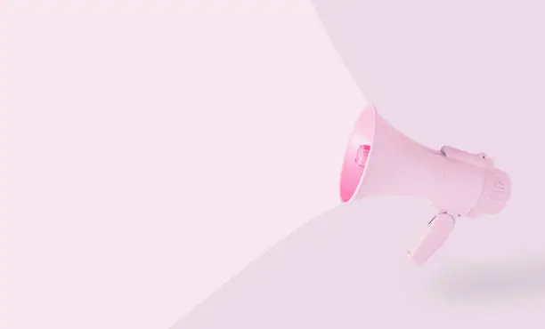 Pink megaphone isolated on pastel beige background. Minimal, abstract, aesthetic creative scene with copy space. Note card promotion concept with loudspeaker. Similar, bright, analogous color harmony.