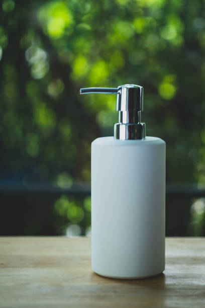 White ceramic pump bottle for liquid soap or shampoo on wood table in home