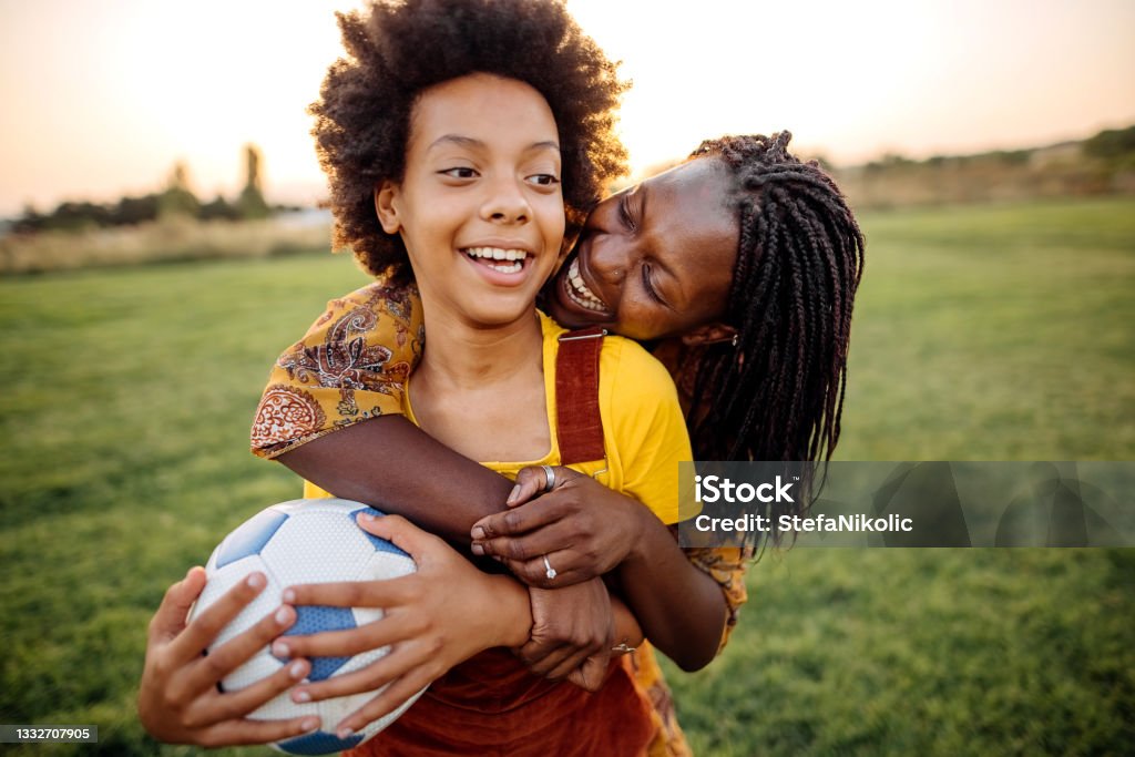 We like to be competitive Mother and daughter playing on filed with ball Child Stock Photo