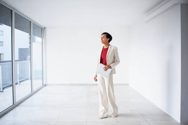 istock Latin real estate agent standing in empty room holding digital tablet 1332707930