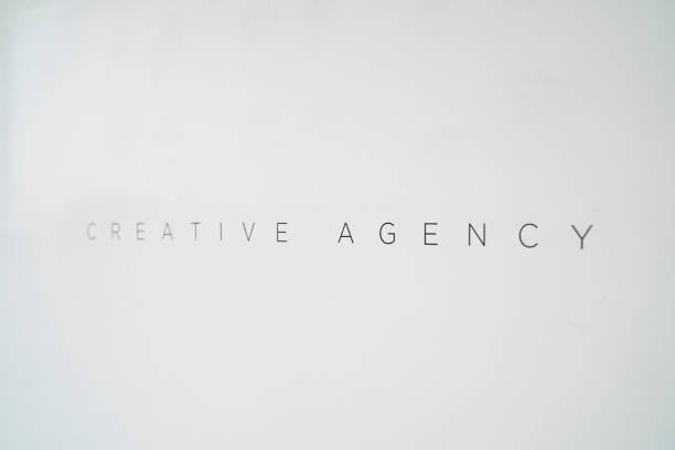Close-up with selective focus of creative agency vinyl text on white wall