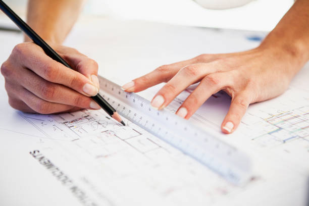 istock Latin female architect hands using pencil and scale ruler while working on blueprint 1332708327