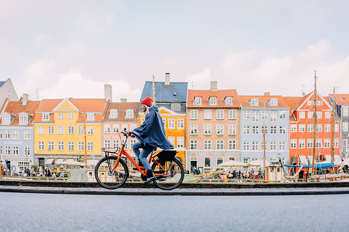 Photo of a smiling young woman cruising the streets of Copenhagen on a bicycle