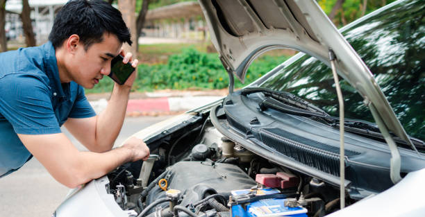 istock Angry Asian man and using mobile phone calling for assistance after a car breakdown on street. Concept of vehicle engine problem or accident and emergency help from Professional mechanic 1332715537