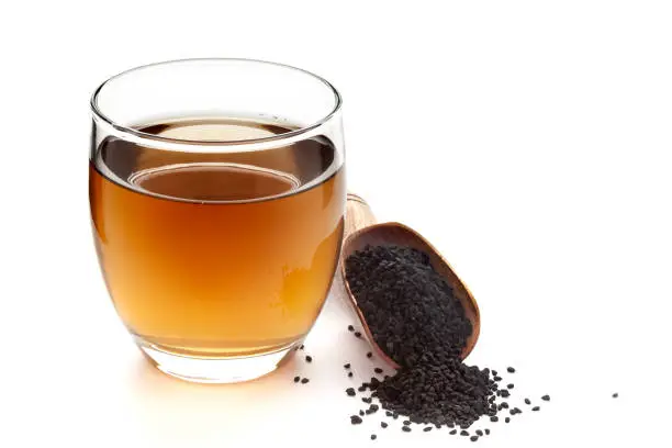 Close-Up of original  organic boiled water (Tea or kada ) of  kalonji (Nigella sativa ) in a transparent glass cup over white background. Original residue in bottom of tea cup