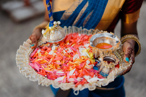 Traditional Indian (Hindi) wedding ceremony -  woman holding plate of flower petals up ready for tossing