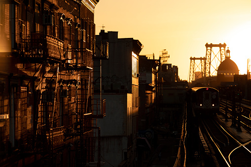 Sunset behind the Williamsburg Bridge cityscape in Brooklyn, New York.