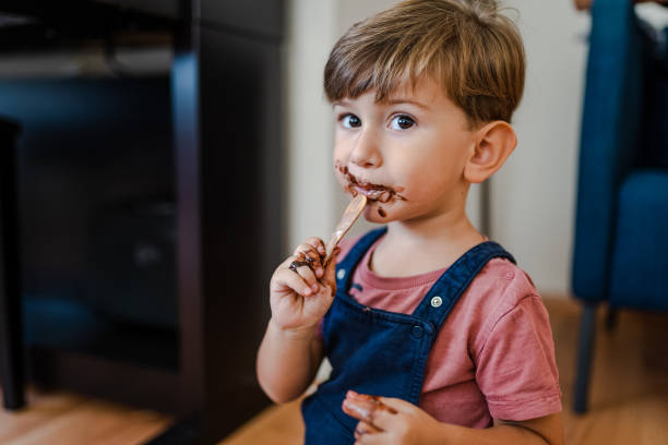 süßer kleiner junge genießt es, zu hause eis zu essen - child chocolate ice cream human mouth stock-fotos und bilder