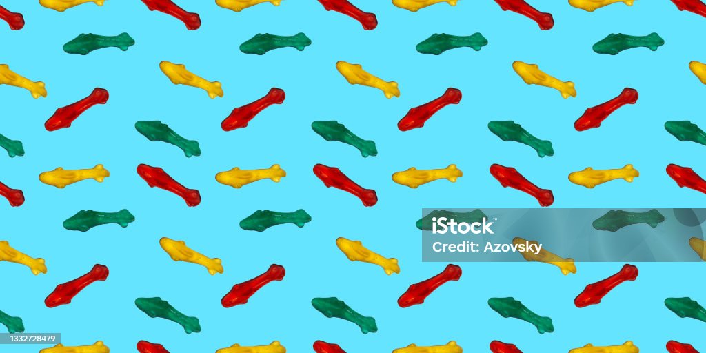 Seamless repeating pattern of marmalade eating sharks. Banner or wallpaper of edible sea fish on a blue sea background. Candy Stock Photo