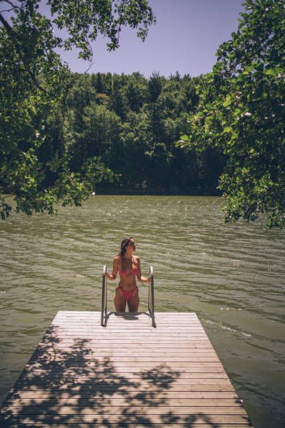 istock Young woman walks down dock ladder, into lake 1332729037