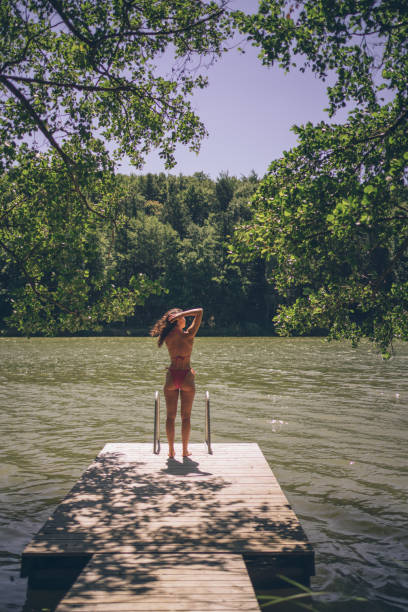 istock Young woman relaxes on lakeside dock in summer 1332729550