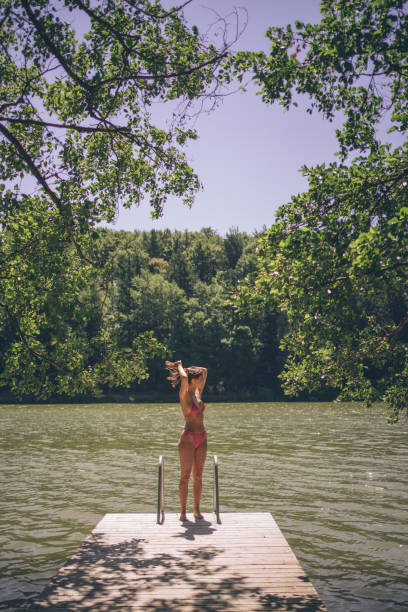 istock Young woman relaxes on lakeside dock in summer 1332729562