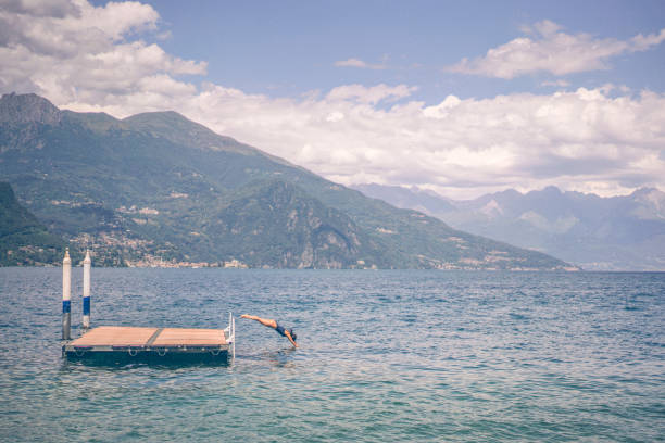 istock Young woman jumps off lakeside dock in summer 1332729564
