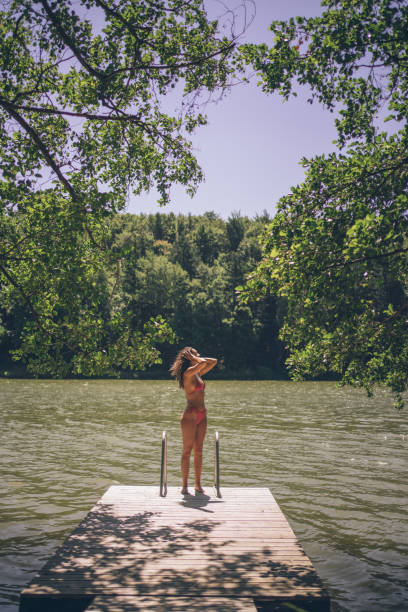 istock Young woman relaxes on lakeside dock in summer 1332729657
