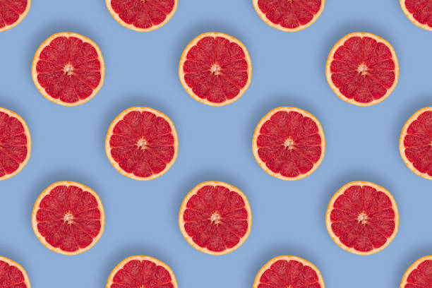 istock Sweet and juicy grapefruits pattern on blue background 1332729878
