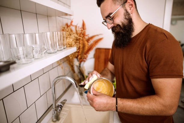 istock Young man washing dishes at home 1332734346