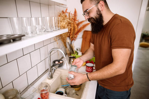 istock Young man washing dishes at home 1332734403