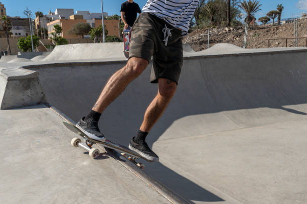 il giovane skateboarder fa un trucco chiamato "rock to fakie" ai margini di una piscina in uno skate park. da vicino - fakie foto e immagini stock