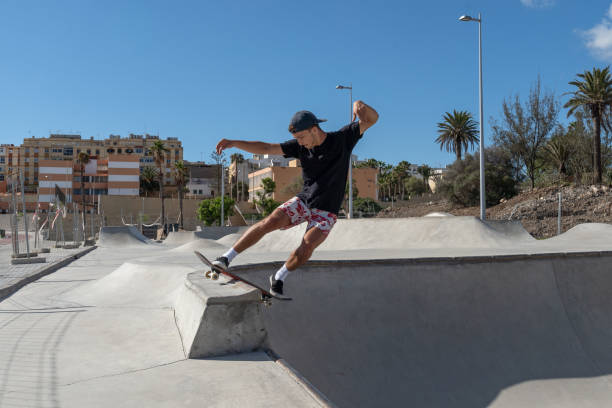il giovane skateboarder fa un trucco chiamato "rock to fakie" ai margini di una piscina in uno skate park. visualizzazione profilo - fakie foto e immagini stock