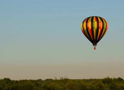 Colorful hot air balloon with white,orange,yellow,green and blue color isolated on blue sky,low angle view