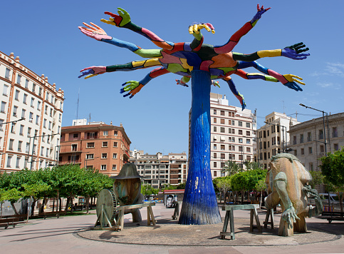 Castellon, Spain. June 14, 2021 - Surrealist fiberglass and bronze fountain sculpture, a tribute to trades, work of the artist Juan Ripolles, 14 meters high and 16 meters wide, with several figures