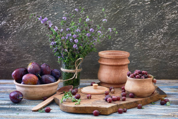 nature morte dans un style de comté: groseille à maquereau, prunes et menthe fraîche sur une table en bois. - crock pot photos et images de collection