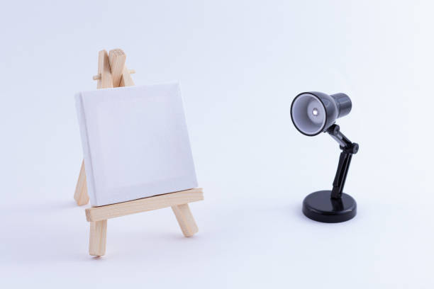 istock Wooden Easel Miniature with Blank White Square Canvas and Table Lamp 1332740794
