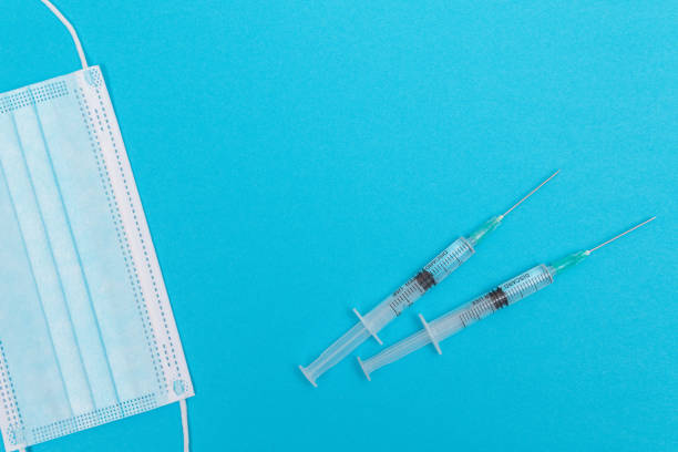 istock Syringe with Medical Mask on Blue Table - Flat Lay 1332741360