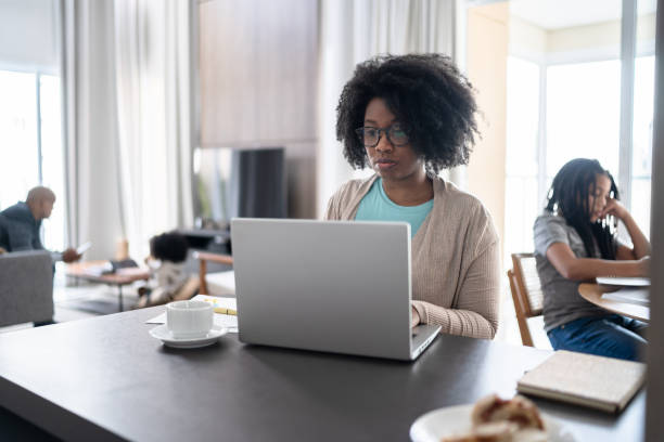 istock Woman using laptop working at home with daughter on the background 1332741443