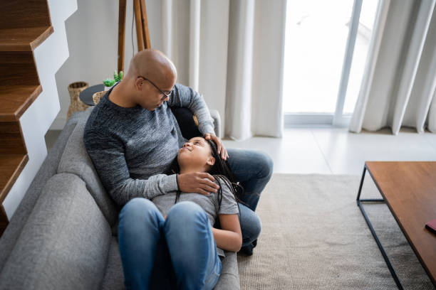 istock Girl lying on father's lap having a conversation at home 1332741476