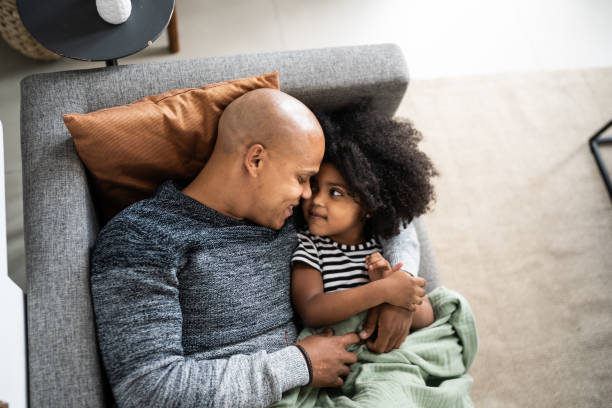 istock Father lying on the couch with daughter at home 1332741482