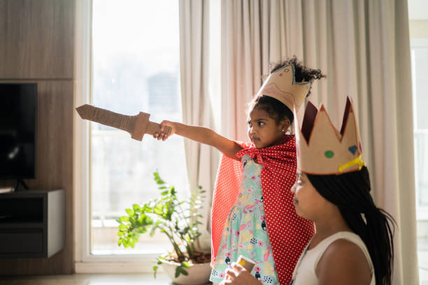 istock Sisters playing with sword and wearing crown at home 1332741738