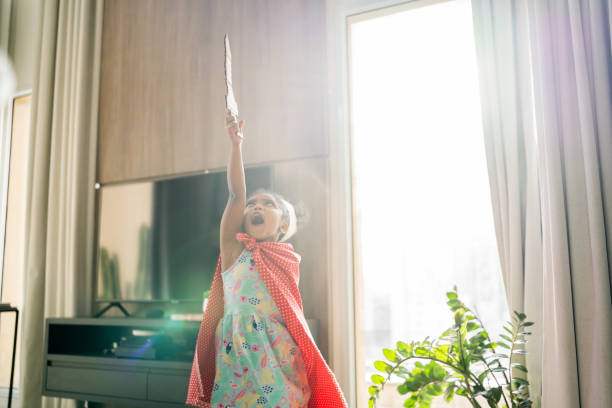 Cute girl is playing with a sword and a crown on her head at home Cute girl is playing with a sword and a crown on her head at home black knight stock pictures, royalty-free photos & images