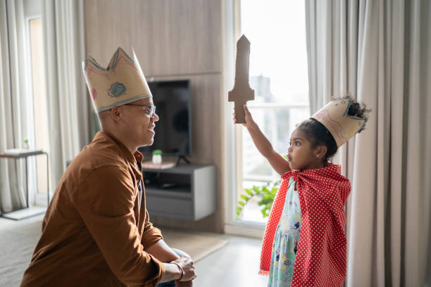 padre e hija jugando con superhéroes en casa - disfrazar fotografías e imágenes de stock