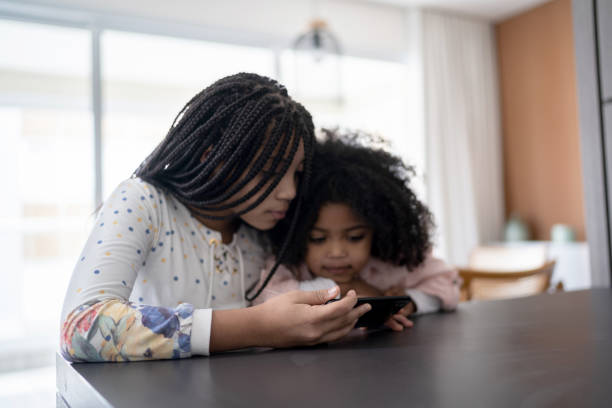 istock Sisters watching something on smartphone at home 1332742079
